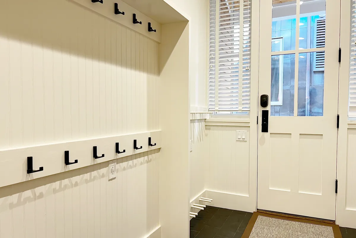 The interior entryway or mudroom, featuring functional hooks on the wall and the front door in view. The space is designed for hanging coats or bags and serves as a practical transition zone between outdoor adventure and indoor comfort.