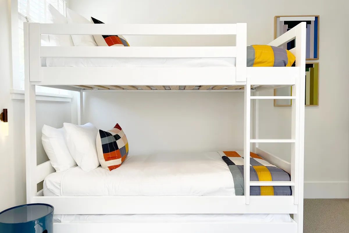 A bright and playful bunk room with two sets of bunk beds, colorful throw pillows, and whimsical wall art. The room exudes a sense of fun and camaraderie, perfect for sleepovers and shared adventures.
